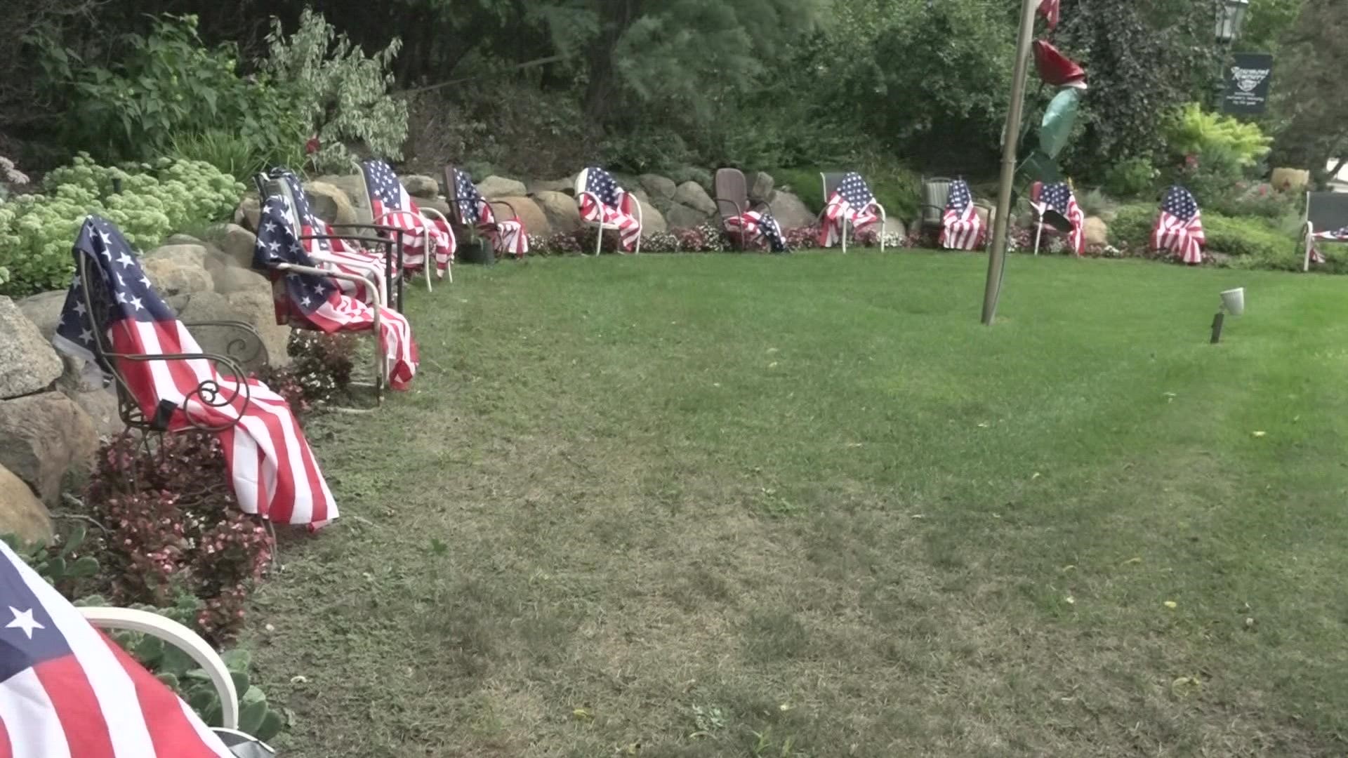 The memorial on Elmridge Drive NW features 13 chairs, each with an American flag draped over it.