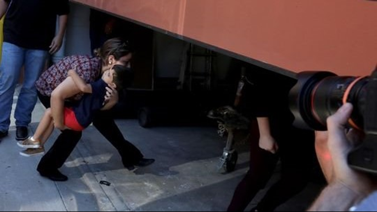 An employee from Bethany Christian Services rushes with one of three immigrant children in through a garage to get inside the U.S. Customs and Immigration Enforcement in Grand Rapids, Michigan on Tuesday, July 10, 2018.