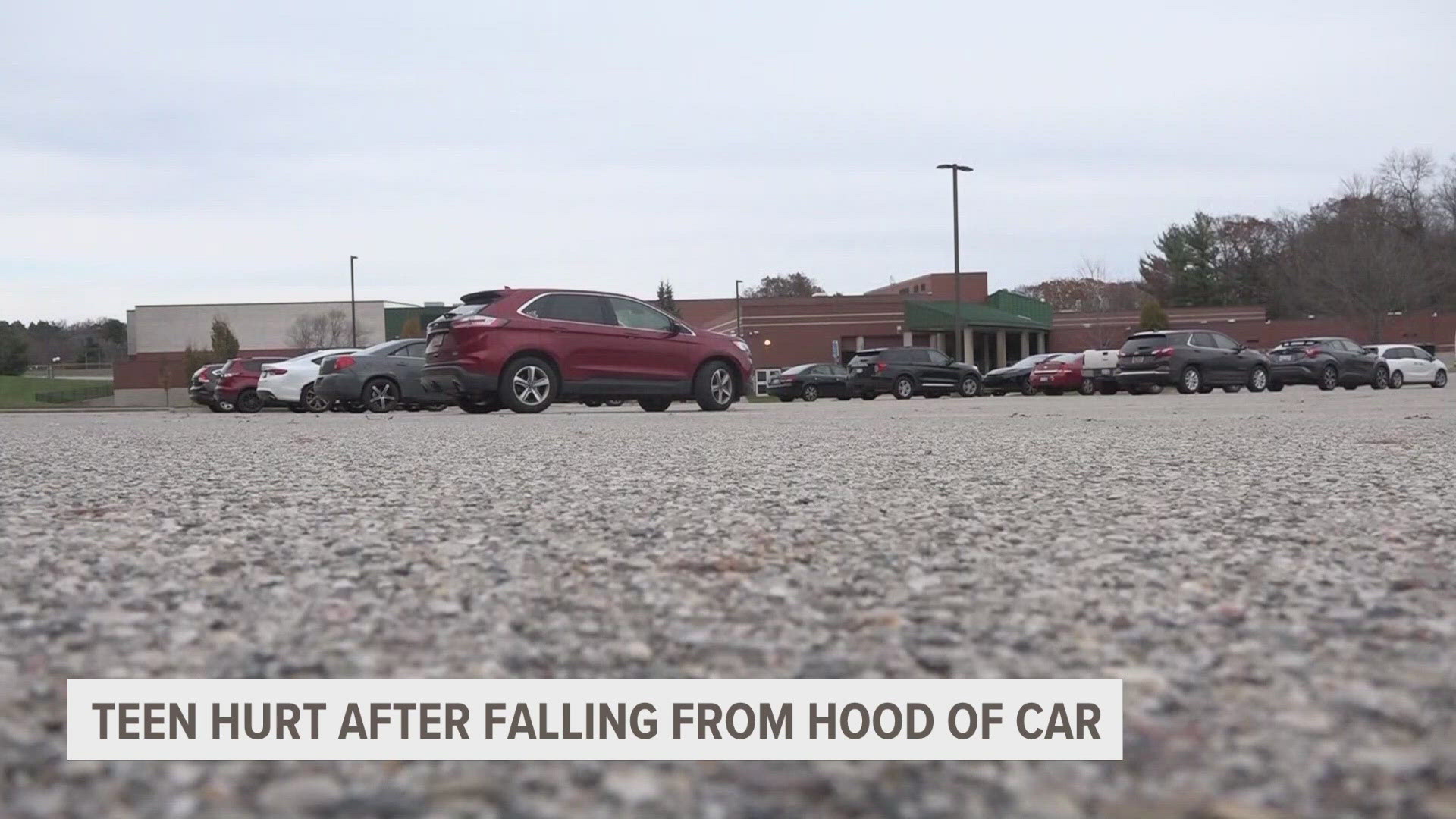 The pair of 17-year-old students were driving through the high school's parking lot, one lying on the hood. When the vehicle turned, they fell off.