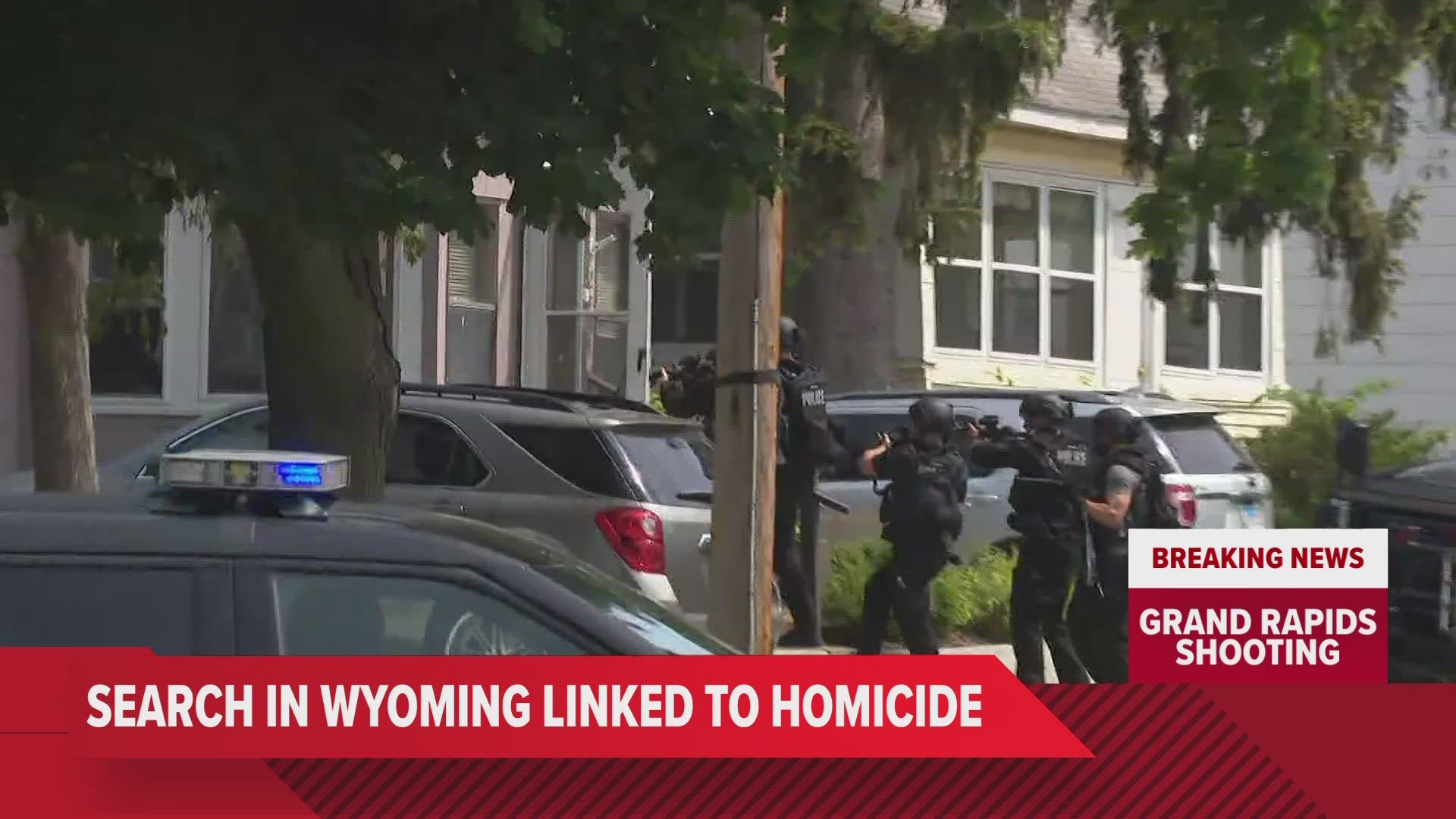 Law enforcement in Wyoming surrounded a home linked to a person of interest in a Grand Rapids homicide case.