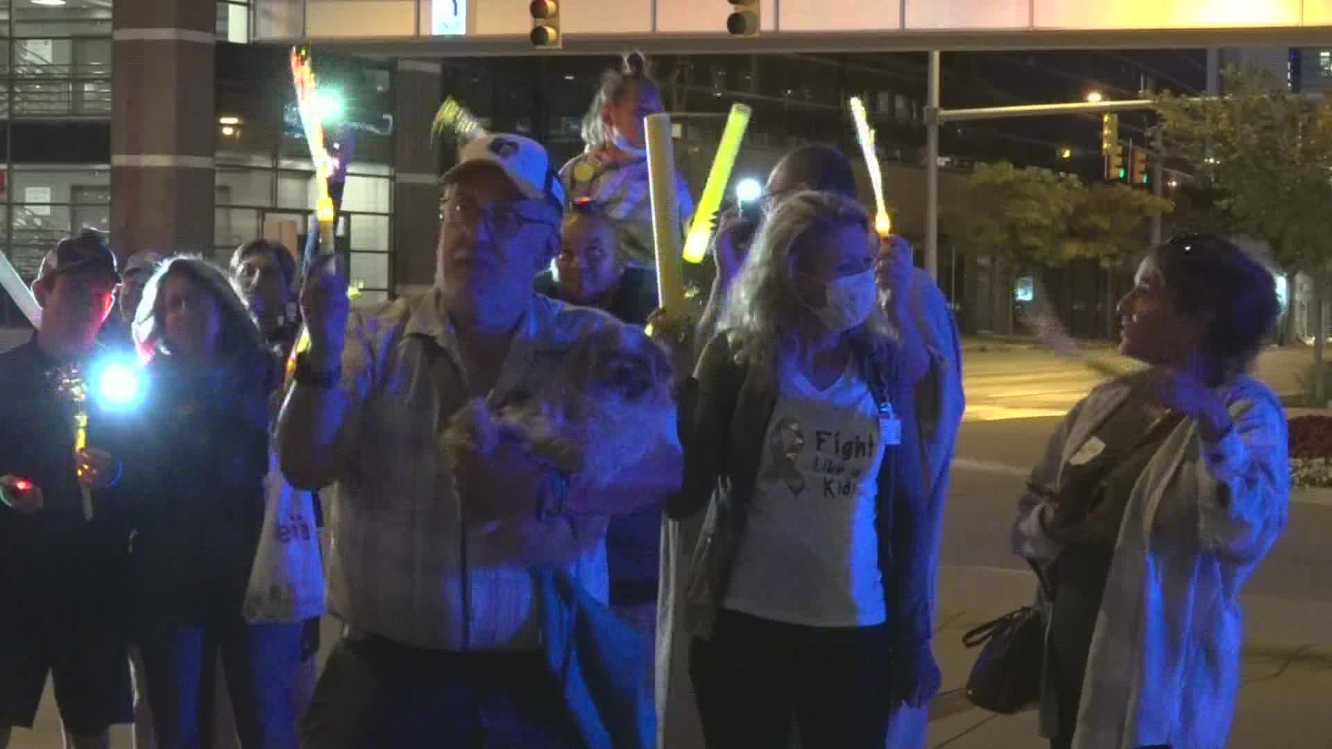 Crowds gathered in support outside of Helen DeVos Children's Hospital, holding gold glow sticks.